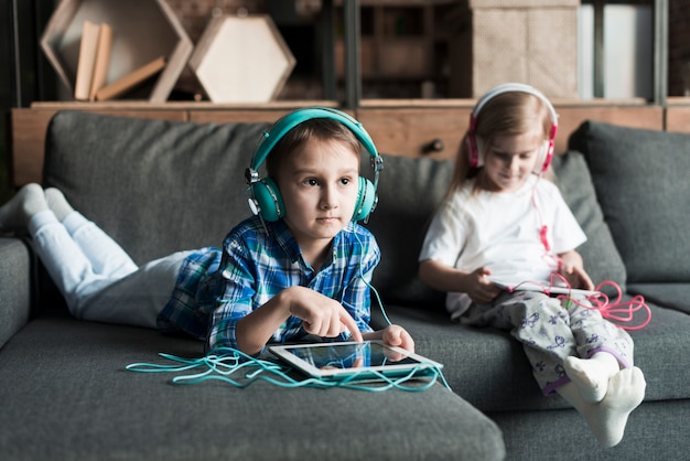 Deux enfants sur le canapé avec des comprimés