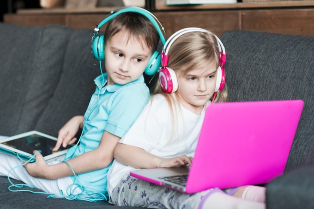 Deux enfants sur le canapé avec un ordinateur portable