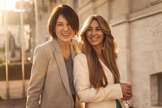 Deux femmes adultes caucasiennes joyeuses en vestes rient en marchant dans la rue journée ensoleillée concept de vie de vacances