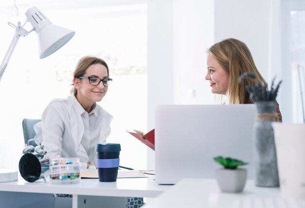 Deux femmes d&#39;affaires souriantes parlant au bureau