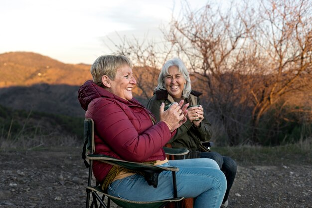 Deux femmes âgées lors d'une escapade dans la nature assises sur des chaises et profitant de leur temps