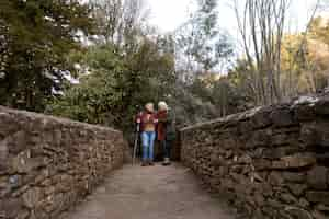 Photo gratuite deux femmes âgées traversant un pont de pierre dans la nature