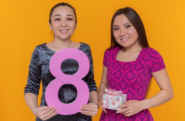 Deux femmes asiatiques heureux célébrant la journée internationale de la femme tenant le numéro huit