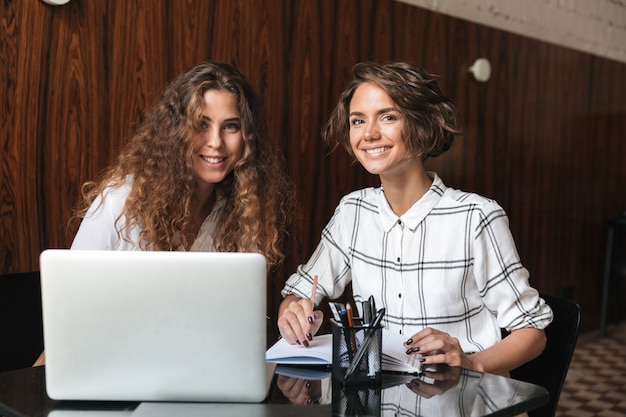 Deux femmes bouclées souriantes travaillant à la table