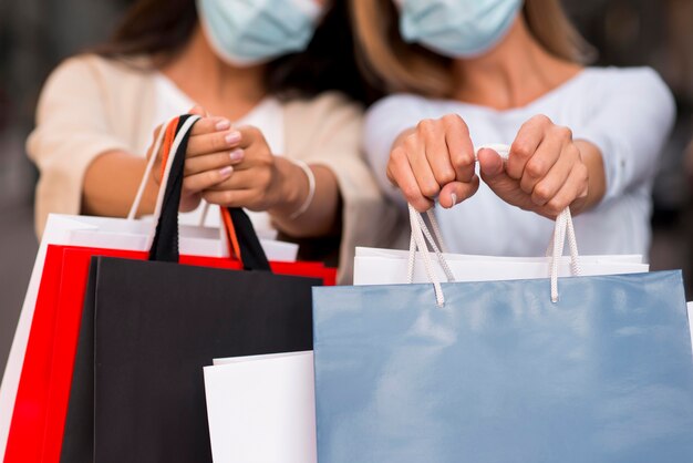 Deux femmes défocalisés avec des masques médicaux tenant des sacs à provisions avec des articles en solde