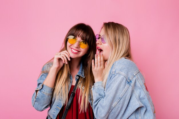 Deux femmes émotionnelles bavardent sur le mur rose