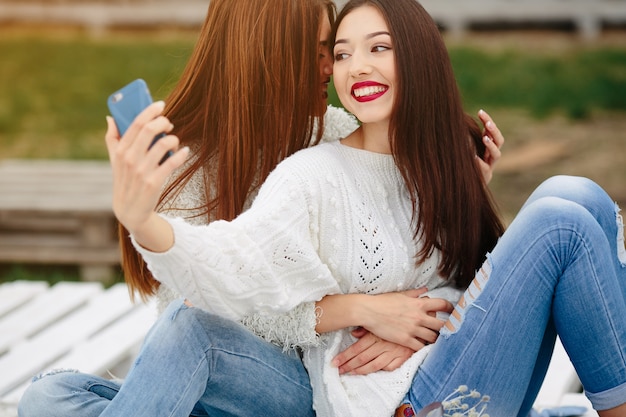 Deux femmes faisant selfie sur le banc dans le parc