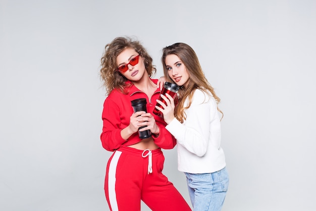 Deux femmes fortes en survêtement rouge et jeans, buvant dans une tasse thermos dans les mains ! Temps pour le thé!