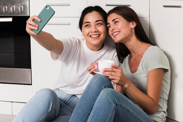 Deux femmes à la maison dans la cuisine prenant un selfie