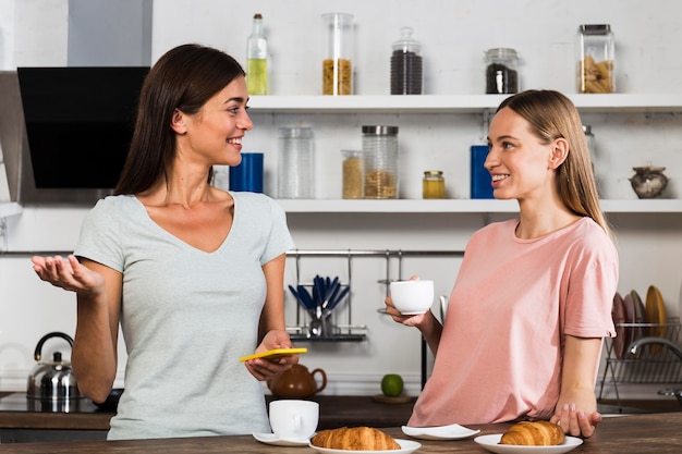 Photo gratuite deux femmes à la maison discutant autour d'une tasse de café