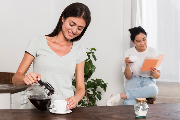Deux femmes à la maison prenant un café et lisant