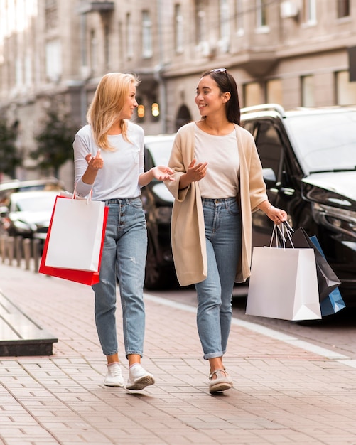 Deux femmes marchant dans la rue tout en tenant des sacs à provisions