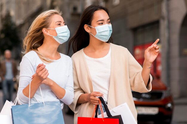 Deux femmes avec des masques médicaux et des sacs à provisions à vendre shopping