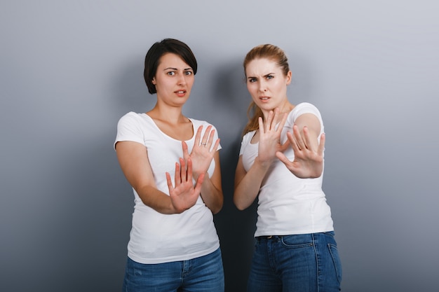 Deux femmes montrant un geste de repousser et en regardant la caméra.