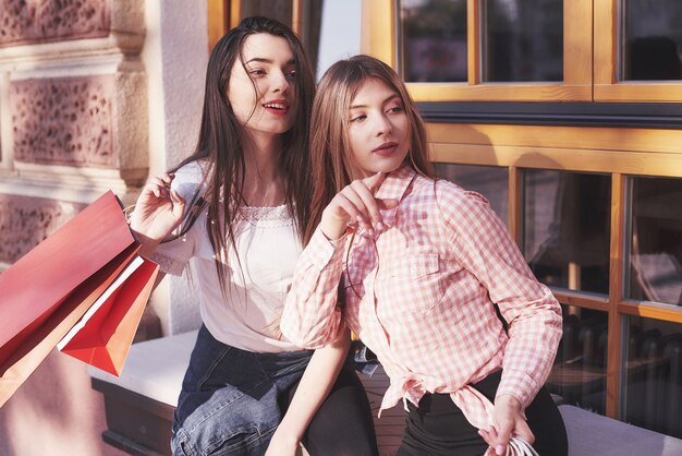 Deux femmes parlent après avoir fait du shopping dans la rue près de la fenêtre.