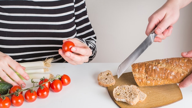 Photo gratuite deux femmes préparent la salade et coupent le pain avec un couteau sur le bureau