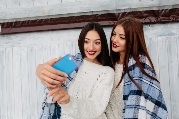 Deux femmes s'assoient sur le banc et font des selfies