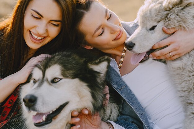 Deux filles élégantes dans un champ ensoleillé avec des chiens