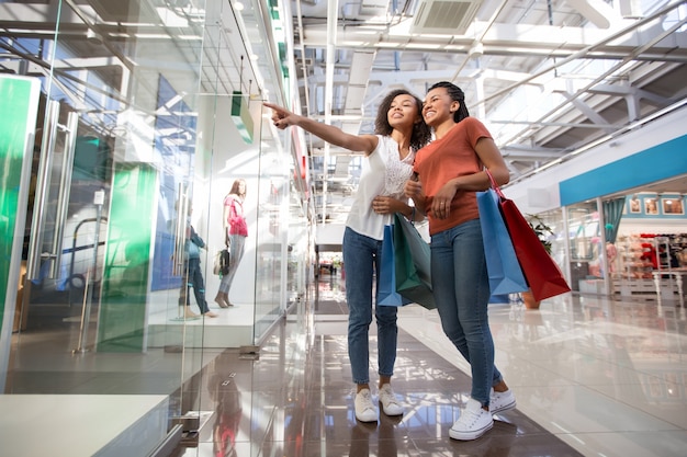 Deux filles noires excitées qui indiquent la fenêtre de la boutique