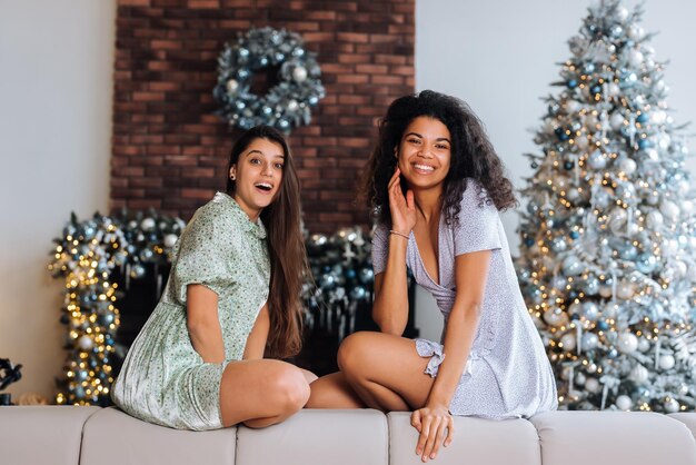 Deux filles sont assises à l'arrière du canapé, regardent les caméras et sourient