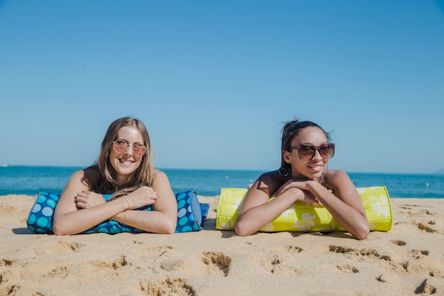 Deux filles souriantes allongées à la plage