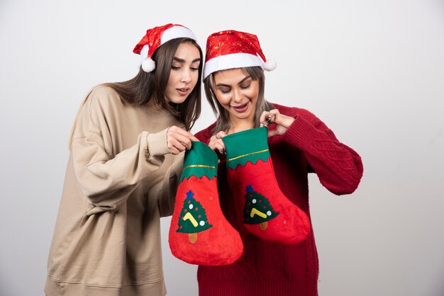 Deux filles souriantes en bonnet de Noel regardant des chaussettes de Noël.