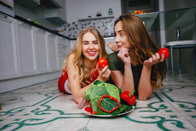 Deux filles sportives dans une cuisine avec des légumes