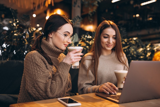 Deux filles travaillant sur un ordinateur dans un café