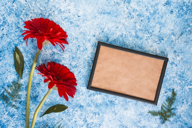 Deux fleurs de gerbera avec cadre vide sur la table