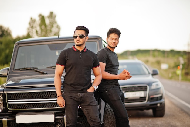 Deux frères asiatiques homme portent sur tout noir posé près de voitures suv