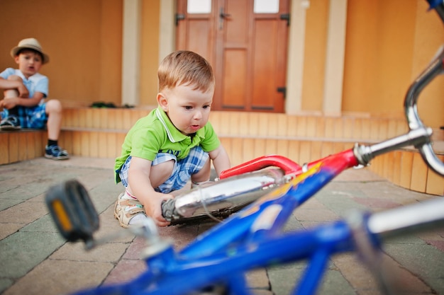 Deux frères réparent le vélo Les petits mécaniciens travaillent avec le vélo