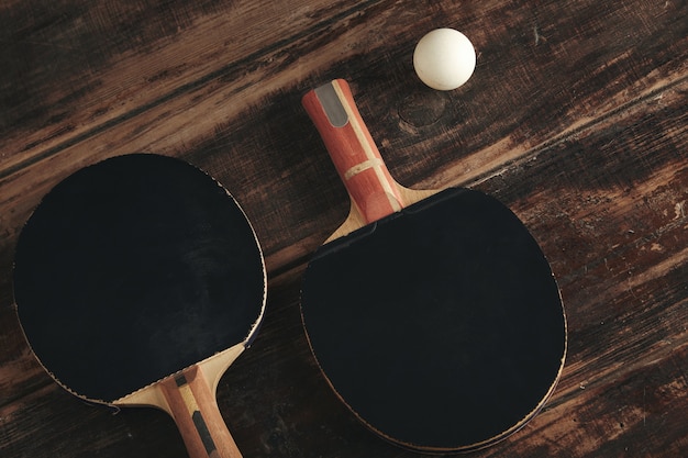 Photo gratuite deux fusées de ping-pong professionnelles allongées sur une table en bois vintage.