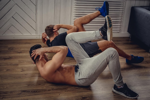 Deux gars faisant des exercices d'estomac sur le sol.