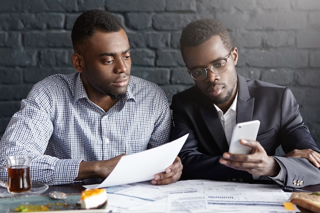 Deux hommes d'affaires afro-américains confiants et sérieux axés sur la paperasse