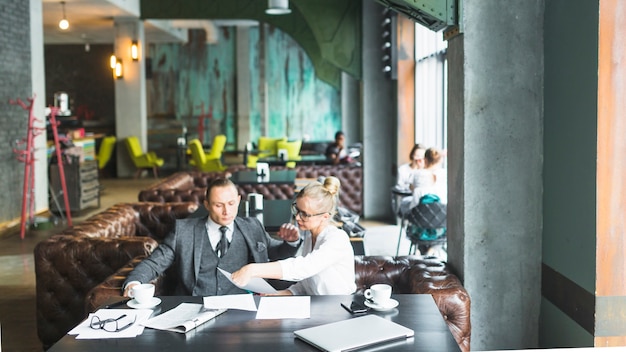 Photo gratuite deux hommes d'affaires assis ensemble vérifiant un document dans un café