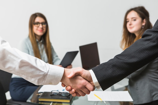 Photo gratuite deux hommes d'affaires se serrant la main devant un cadre féminin au lieu de travail