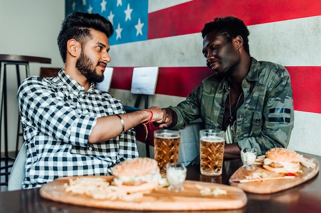 Photo gratuite deux hommes sont assis ensemble dans un bar ou un restaurant se donnent la main