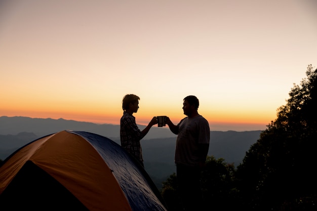 Deux hommes touristes heureux au sommet de la montagne près du feu de camp