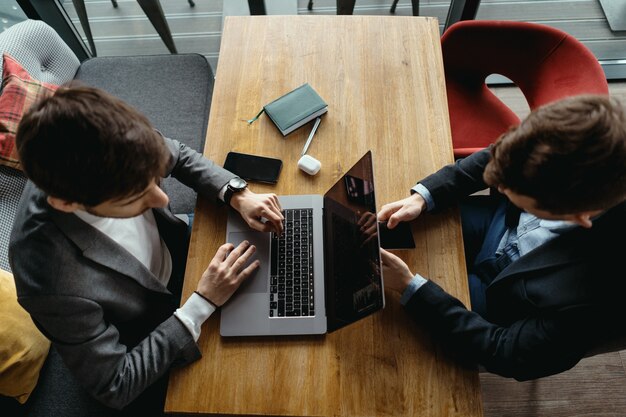 Deux hommes travaillant sur ordinateur portable lors d'une réunion dans un café