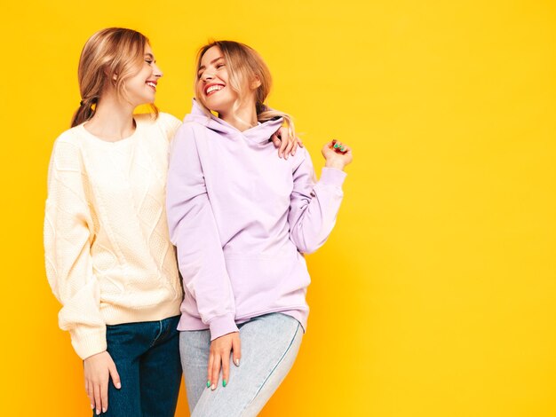 Deux jeunes belles femmes hipster brune souriante dans des vêtements d'été à la mode femmes insouciantes posant près du mur jaune en studio Modèles positifs s'amusant Gai et heureux