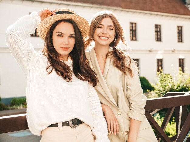 Deux jeunes belles femmes hipster souriantes en pull et manteau blancs à la mode