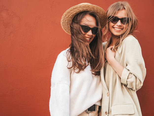 Deux jeunes belles femmes hipster souriantes en pull et manteau blancs à la mode