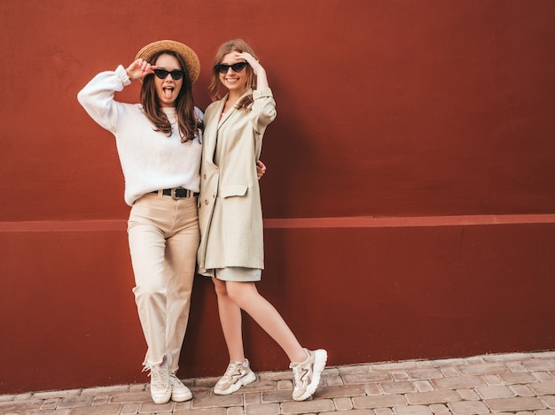 Photo gratuite deux jeunes belles femmes hipster souriantes en pull et manteau blancs à la mode