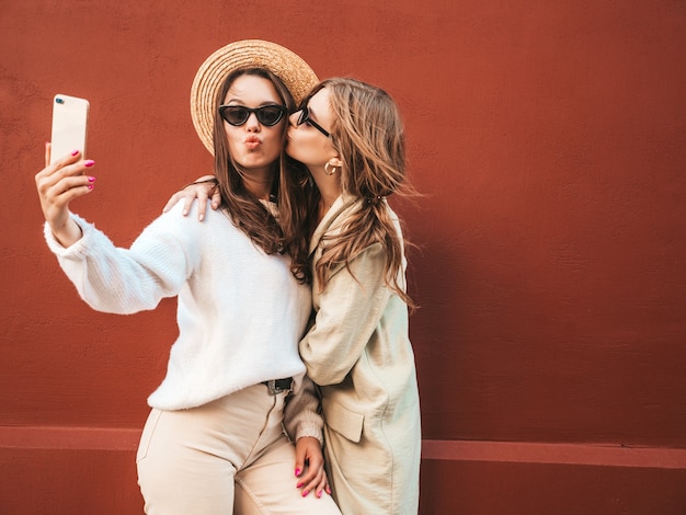 Deux Jeunes Belles Femmes Hipster Souriantes En Pull Et Manteau Blancs à La Mode