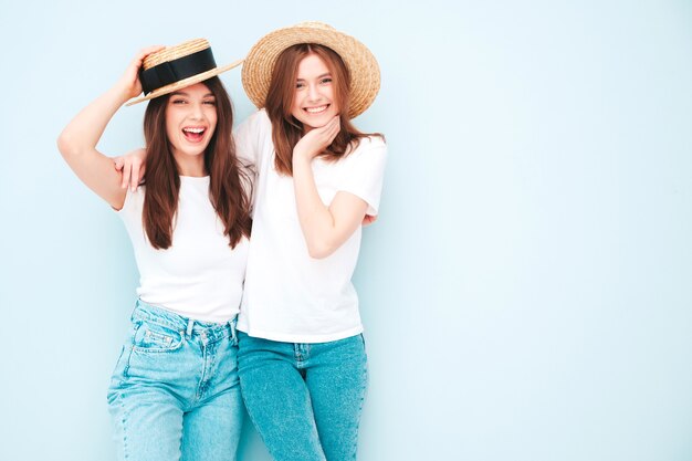 Deux jeunes belles femmes hipster souriantes en t-shirt blanc d'été à la mode et vêtements en jeans