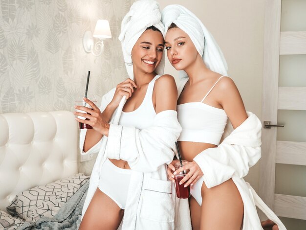 Deux jeunes belles femmes souriantes en peignoirs blancs et serviettes sur la tête