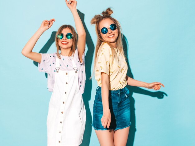 Deux jeunes belles filles blondes blondes souriantes dans des vêtements de T-shirt coloré d'été à la mode.