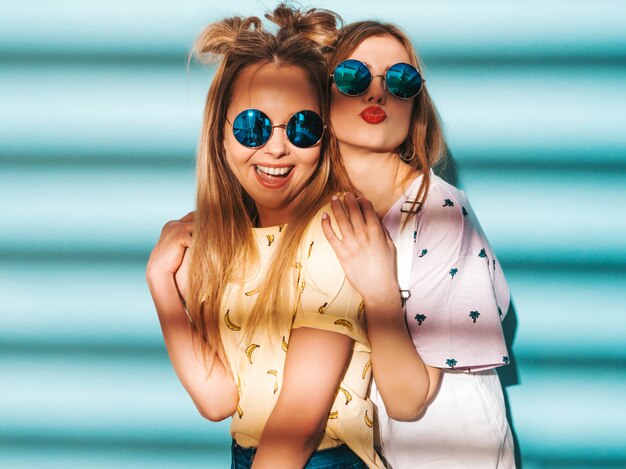 Deux jeunes belles filles blondes blondes souriantes dans des vêtements de T-shirt coloré d'été à la mode.