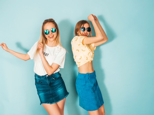 Deux Jeunes Belles Filles Blondes Blondes Souriantes Dans Des Vêtements De T-shirt Coloré D'été à La Mode.