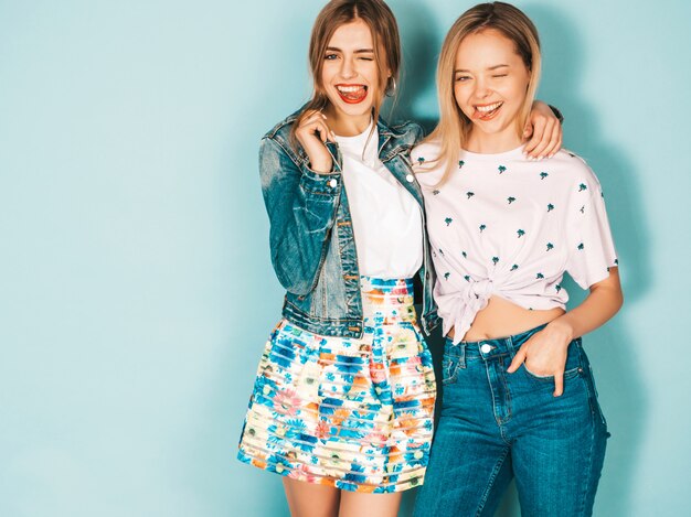 Deux jeunes belles filles blondes hipster blond souriant dans des vêtements colorés d'été à la mode.